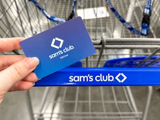 Someone holding a Sam's Club gift card near a cart