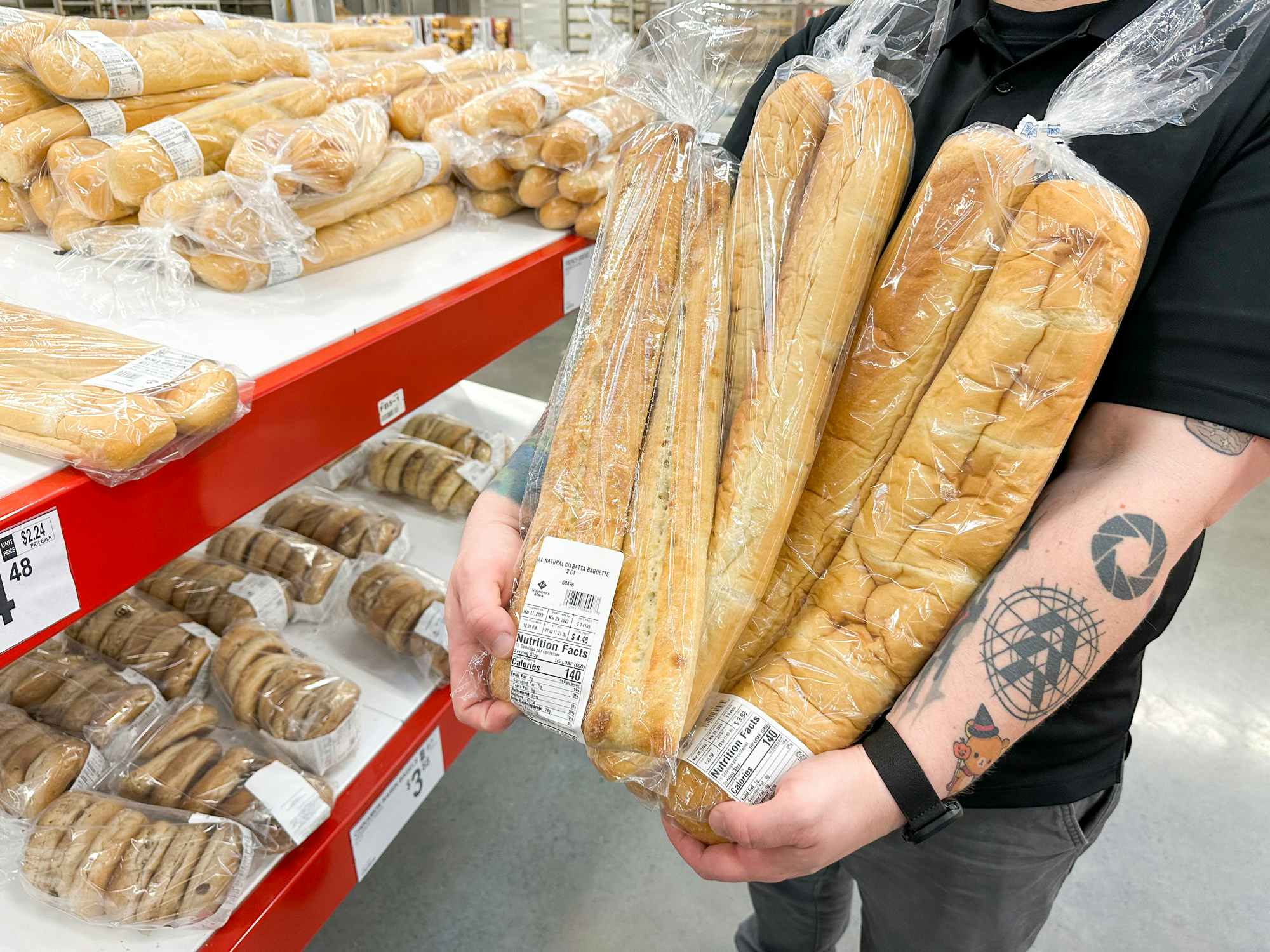 Someone holding a bunch of bread int he bakery section at Sam's Club