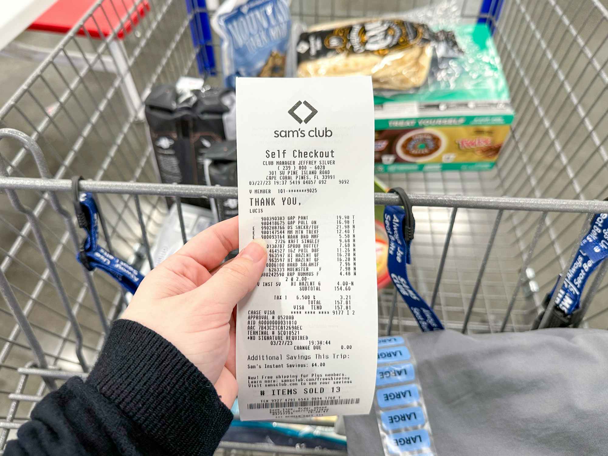 Someone holding their receipt in front of a Sam's Club cart