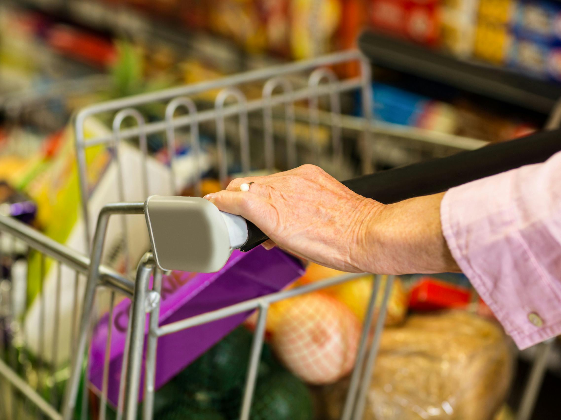 Close up of a senior woman's hand pushing a grocery cart