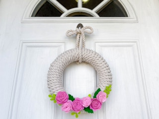 A rope and felt flower wreath hanging on a door