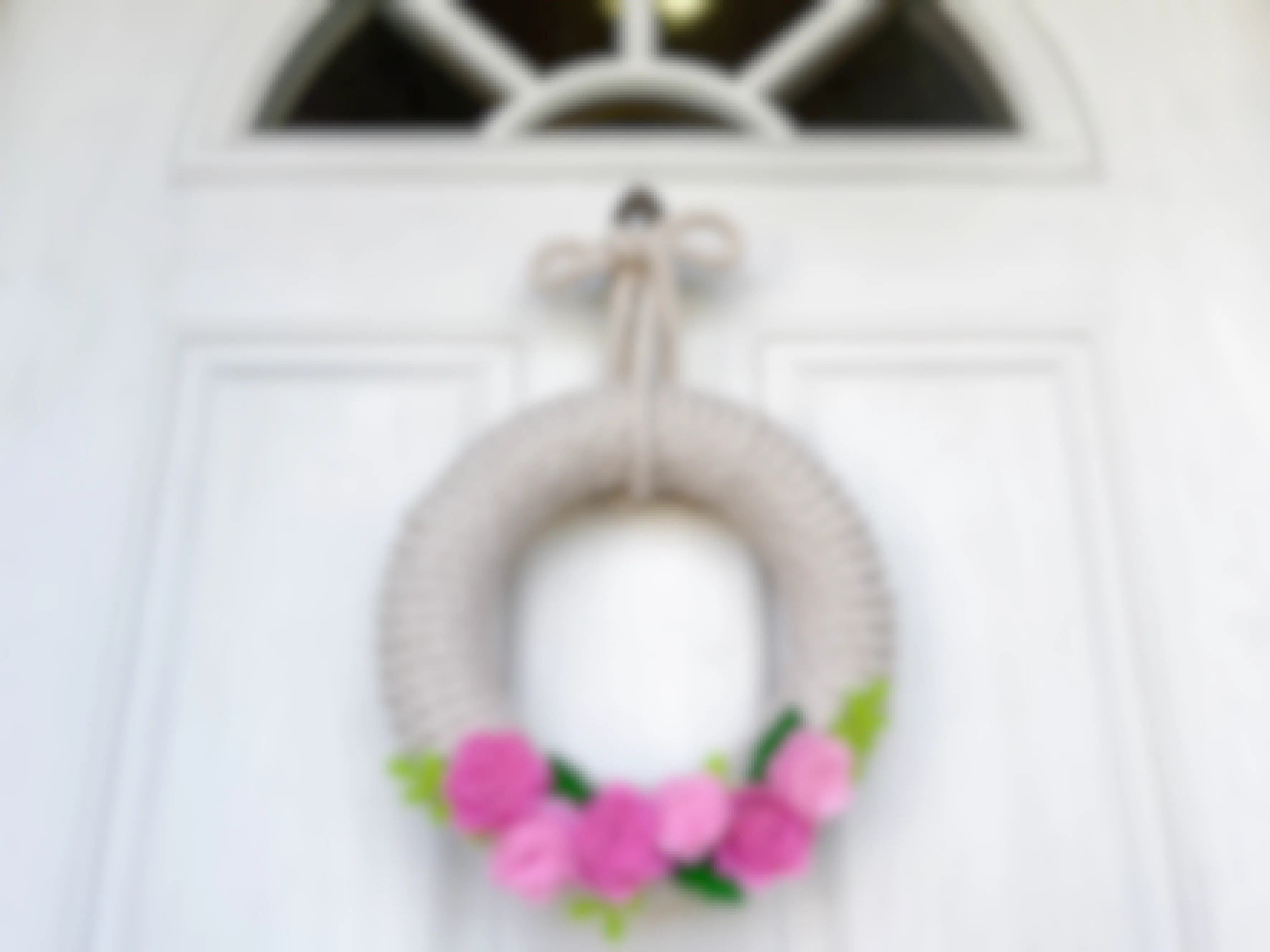 A rope and felt flower wreath hanging on a door 