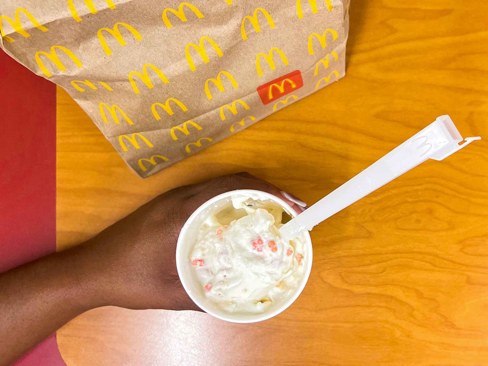 hand holding the mcdonalds limited-time strawberry shortcake mcflurry on table near bag