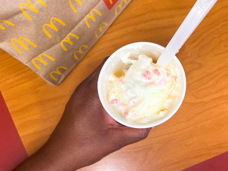 hand holding the mcdonalds limited-time strawberry shortcake mcflurry on table near bag