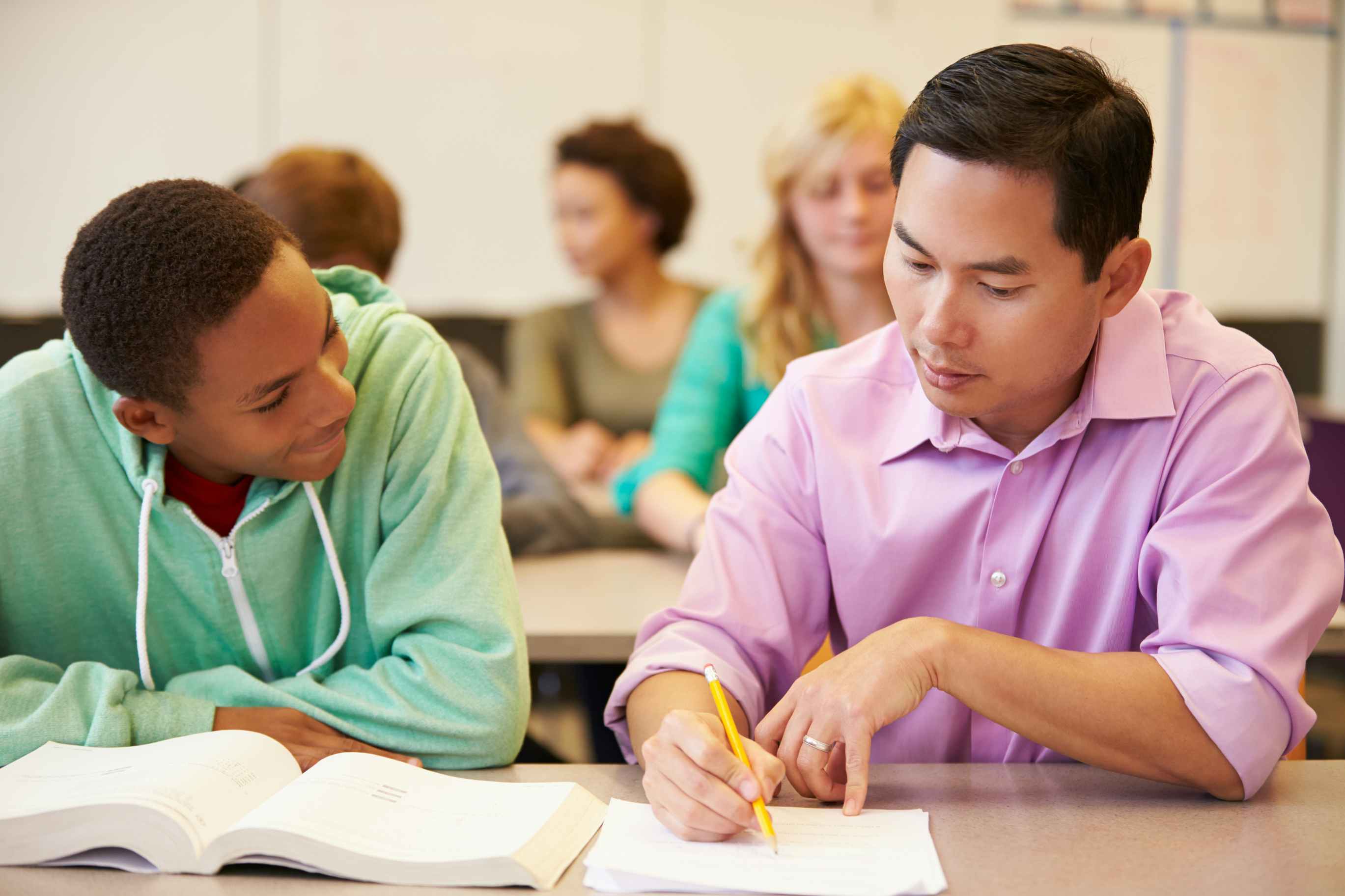 Teacher helping a student writing 