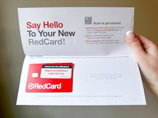 A woman's hang holding up the Target RedCard welcome letter that says "Say Hello To Your New RedCard" with the Target RedCard debit card attached to the letter