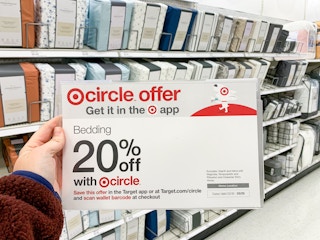 A woman's hand holding a sign that says Bedding is 20% off with Target Circle in the bedding aisle at Target