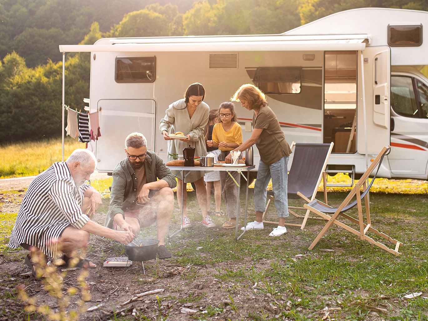family outside camper with food and fire