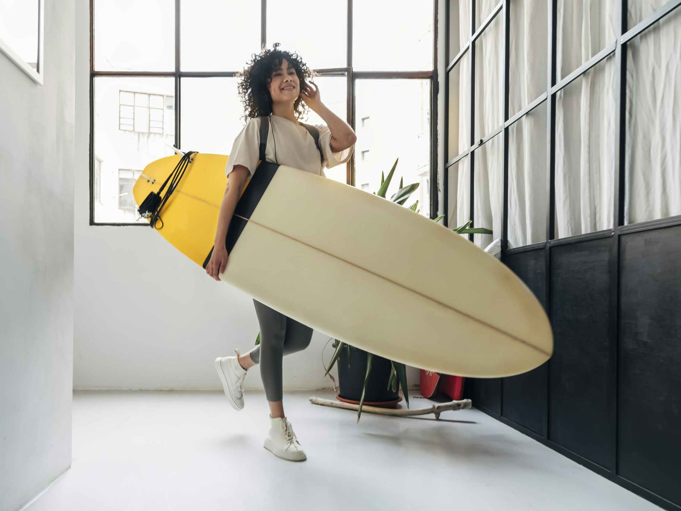 A young person carrying a surfboard inside of a building