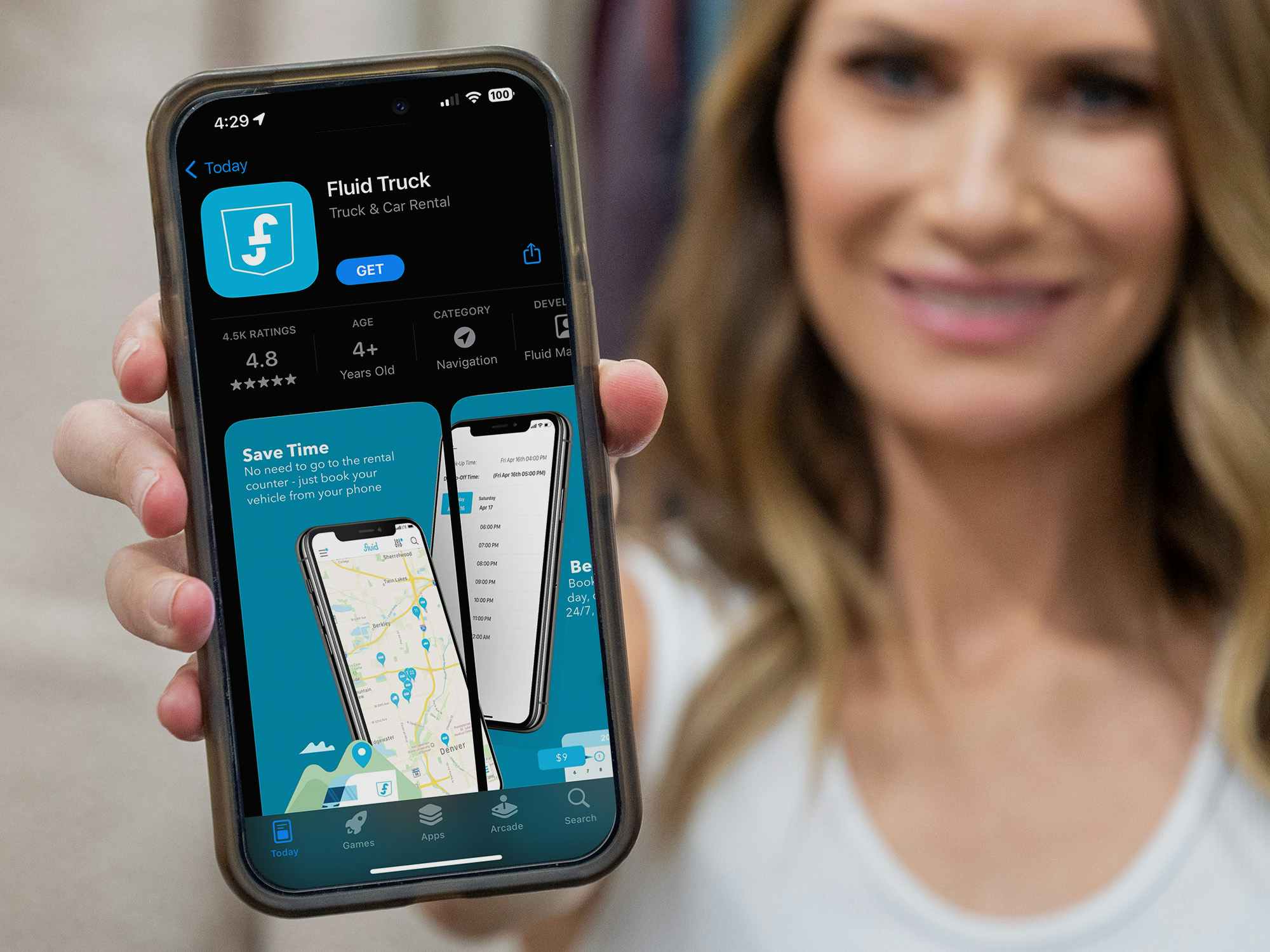A person holding up a phone displaying the App Store page for the app FluidTruck
