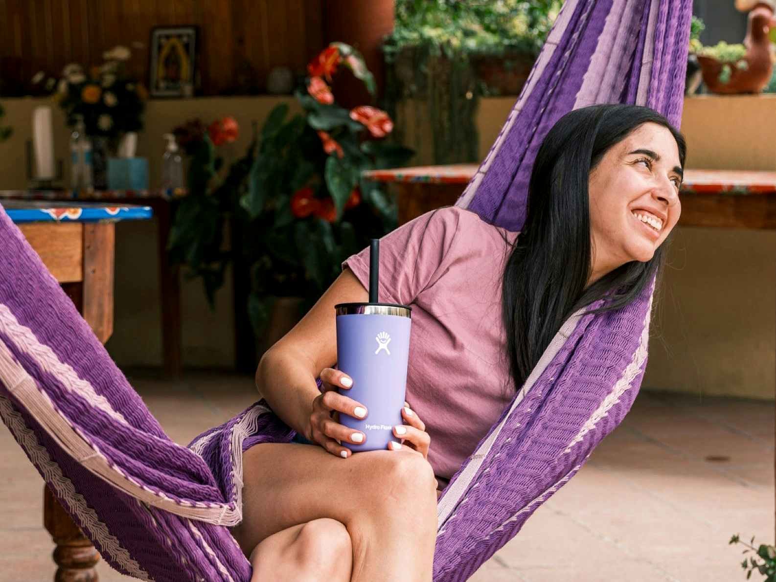 happy person in hammock holding purple hydro flask bottle