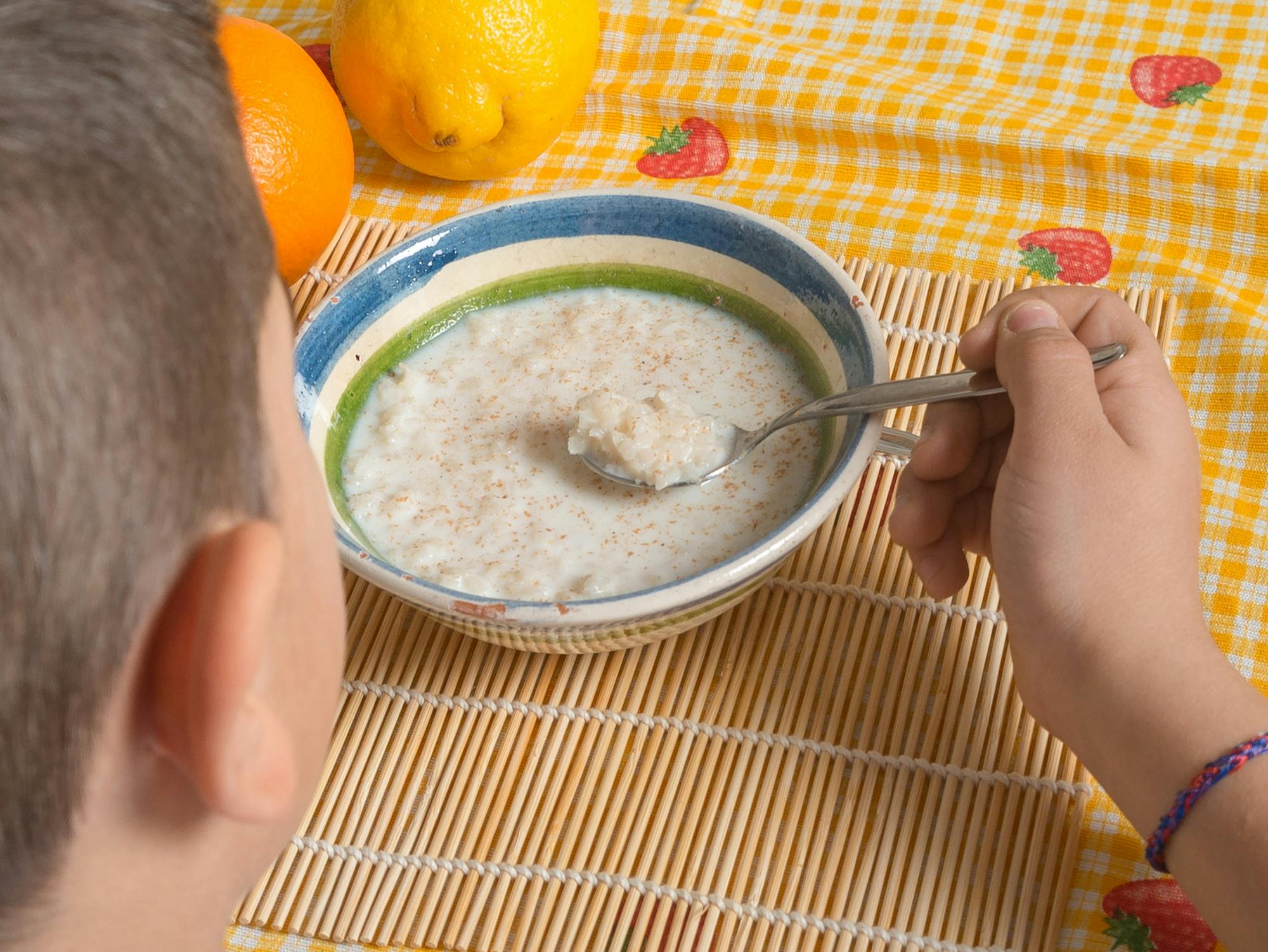 a child putting rice pudding on their spoon before they eat it