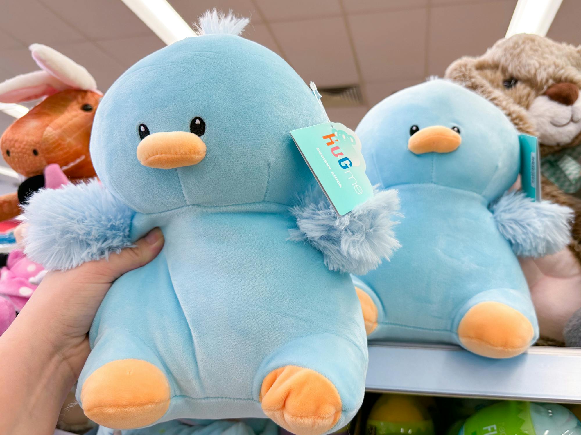 Someone taking a squishy blue chick stuffed animal from a shelf at Walgreens