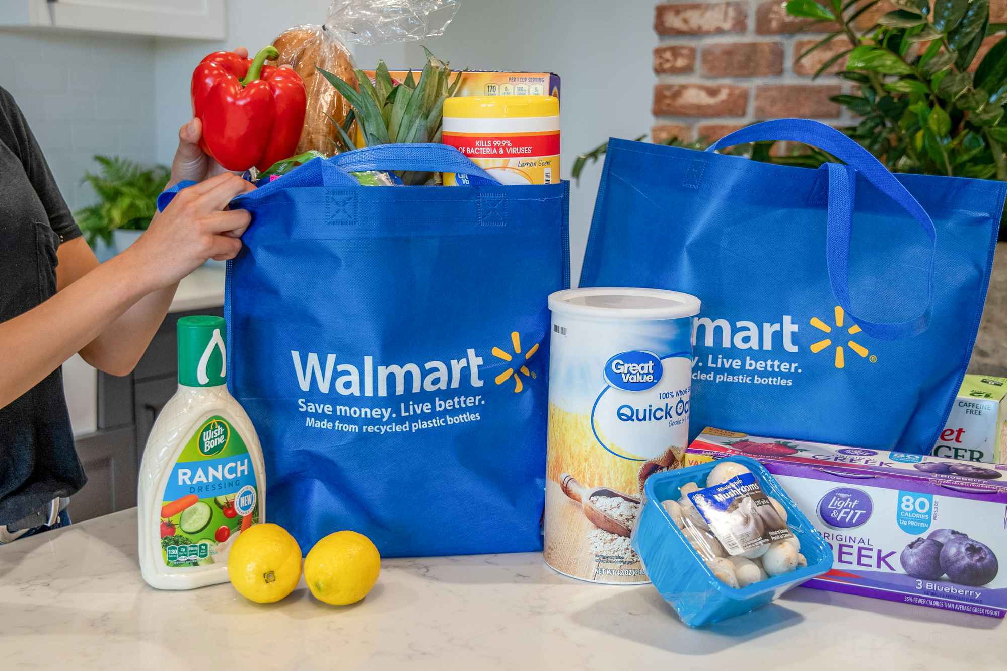 A woman pulling groceries out of Walmart reusable grocery bags.