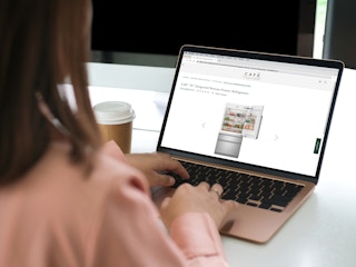 person on laptop shopping for cafe fridge appliance online