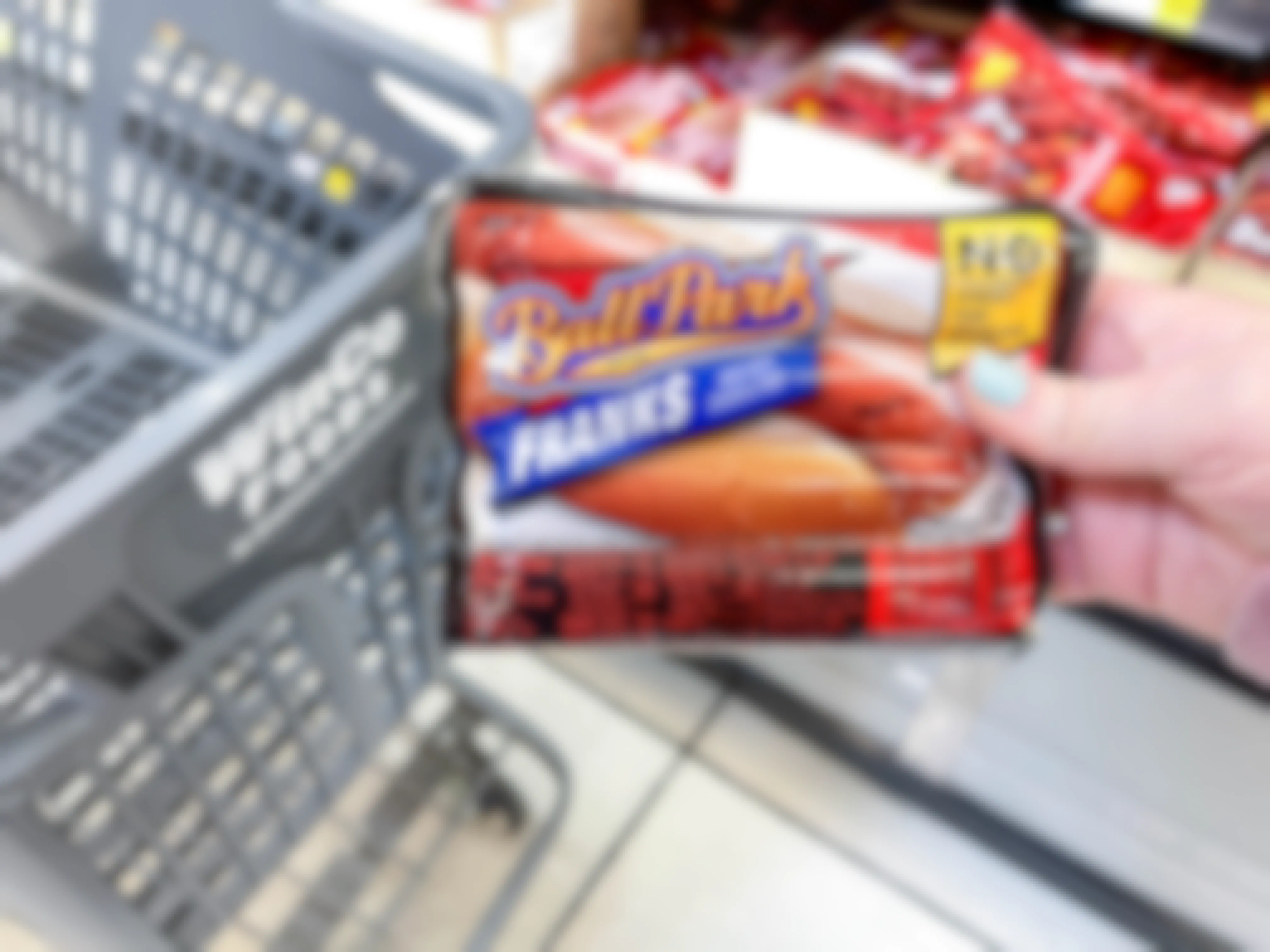 a person holding up ballpark hot dogs in front of cart