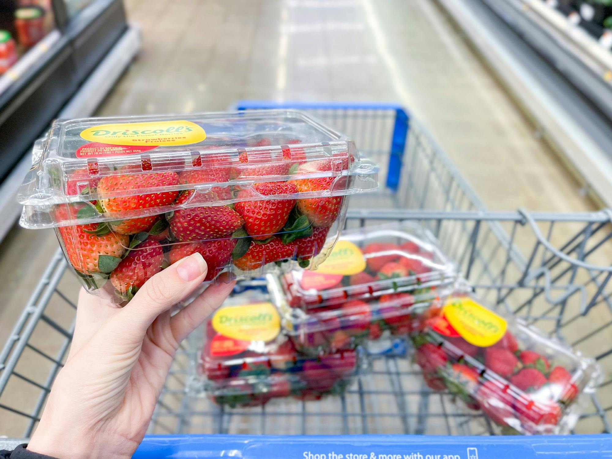 person holding strawberries at walmart 