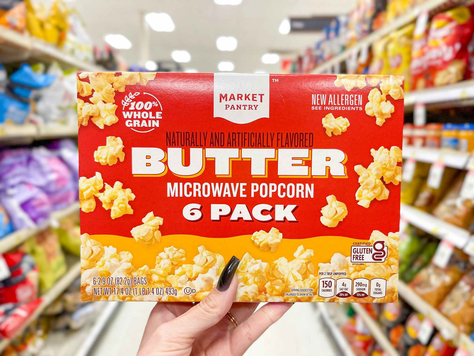Someone holding up a box of Market Pantry microwave popcorn in a Target aisle
