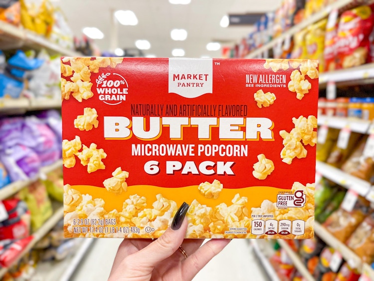 Someone holding up a box of Market Pantry microwave popcorn in a Target aisle