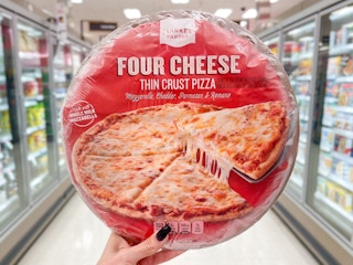 Someone holding up a Market Pantry frozen pizza in a Target aisle