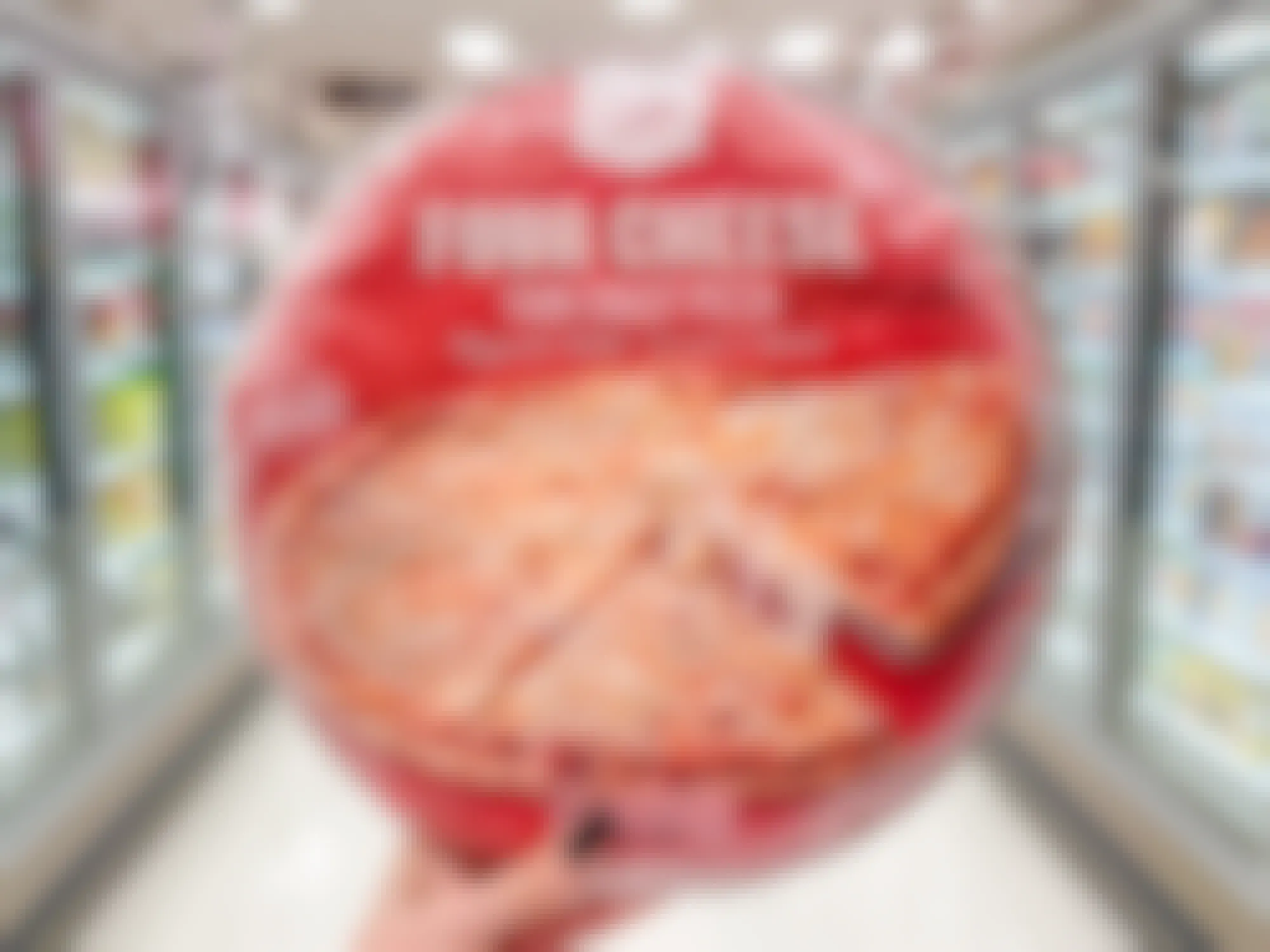 Someone holding up a Market Pantry frozen pizza in a Target aisle