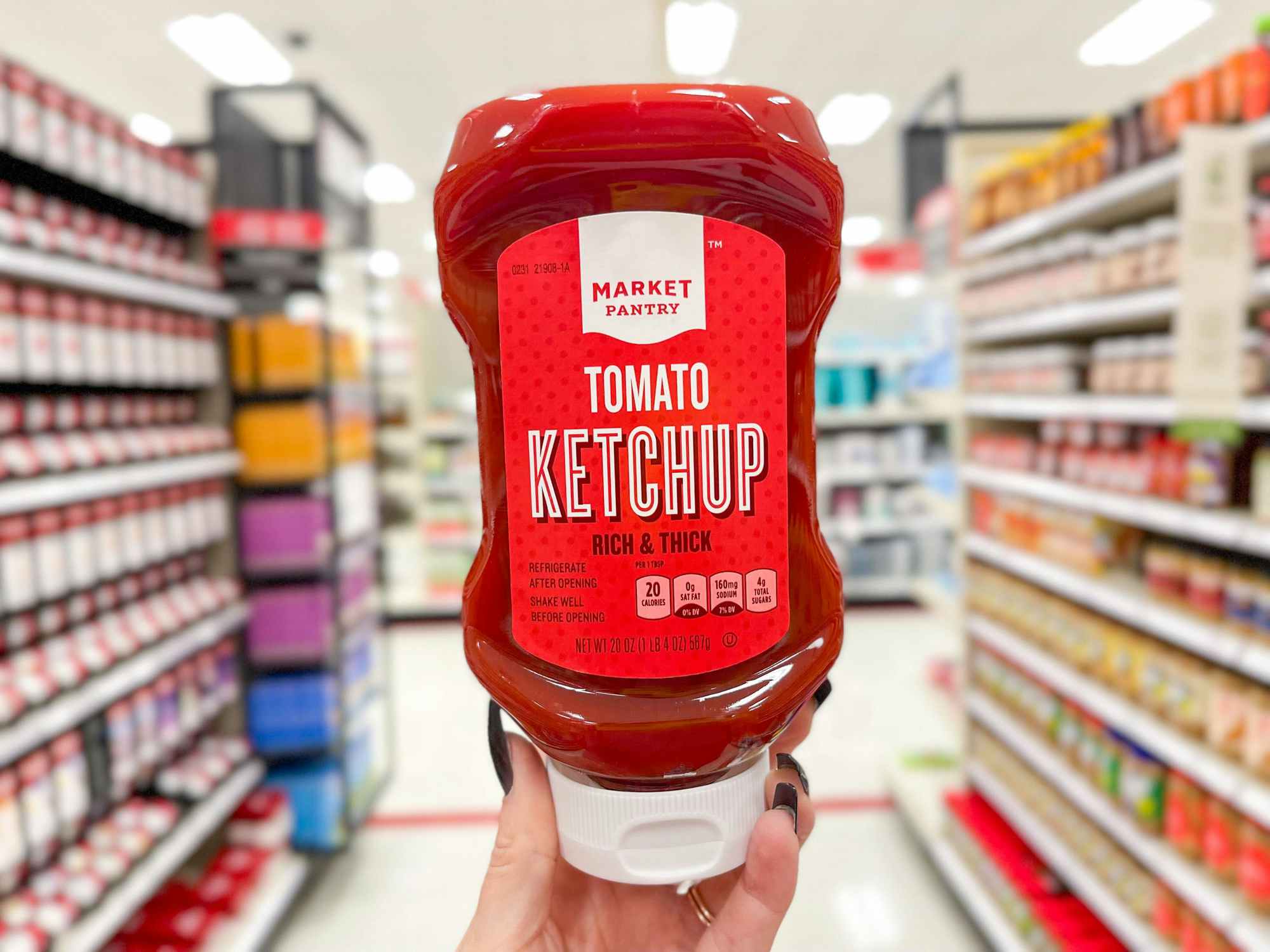 Someone holding up a bottle of Market Pantry ketchup in a Target aisle
