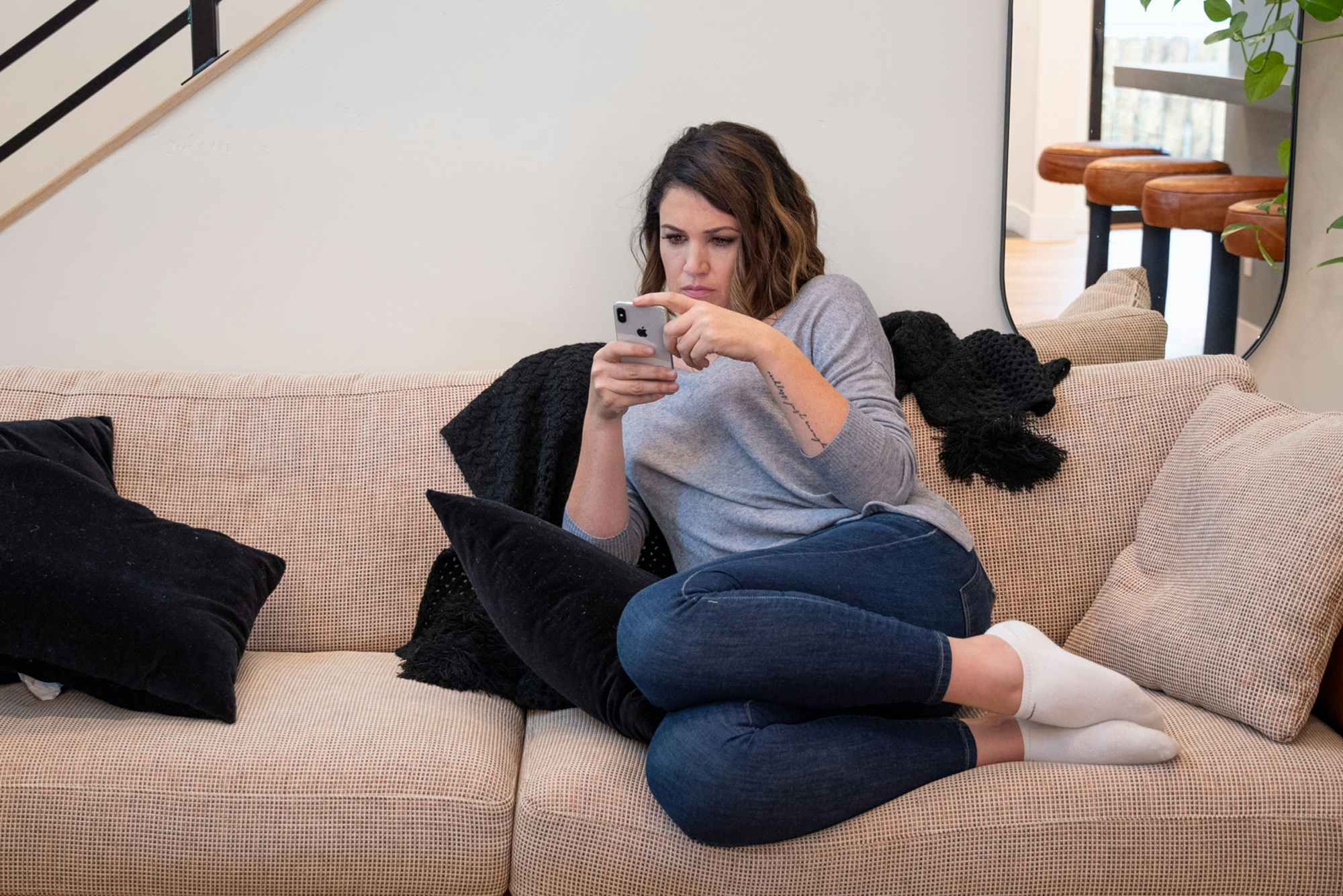 a person looking at a cell phone while sitting on a sofa