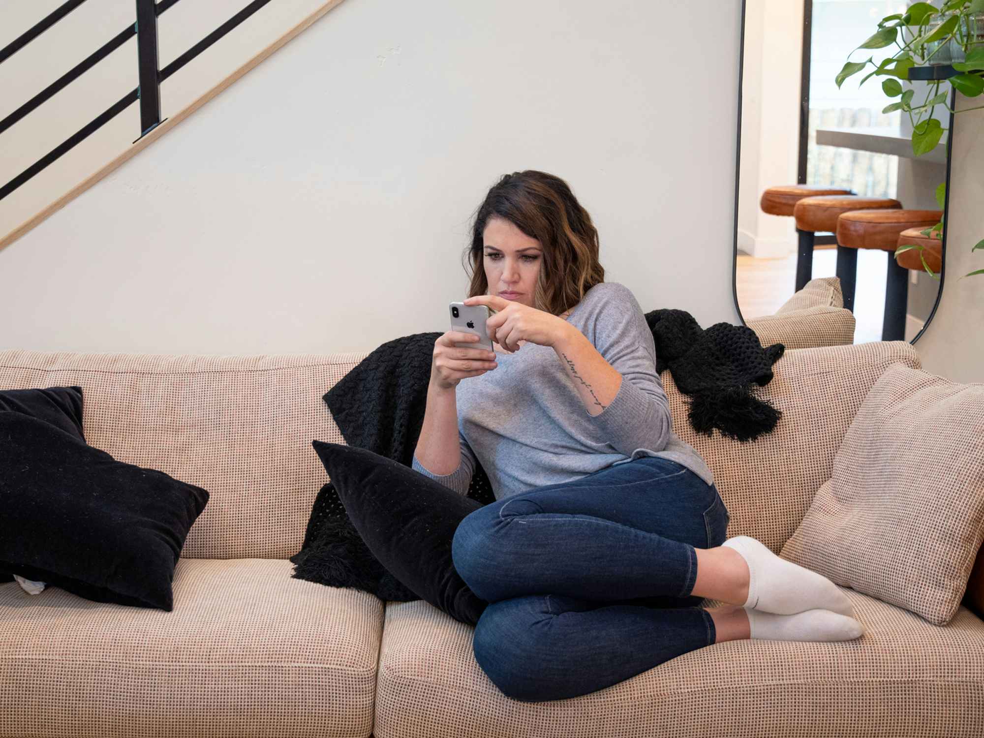 a person looking at a cell phone while sitting on a sofa
