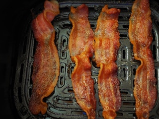 cooked bacon in an air fryer tray