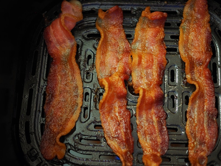 cooked bacon in an air fryer tray 