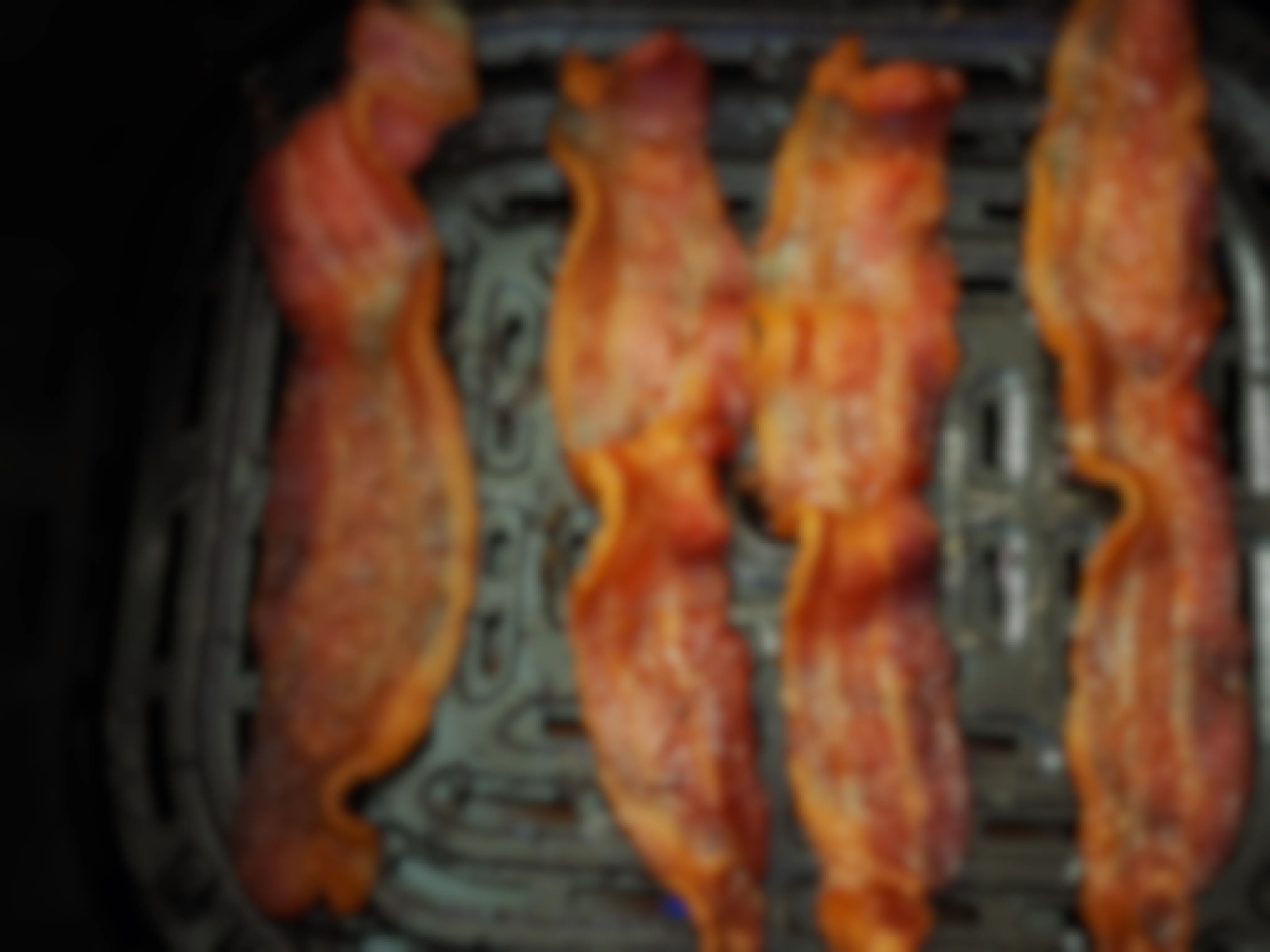 cooked bacon in an air fryer tray 
