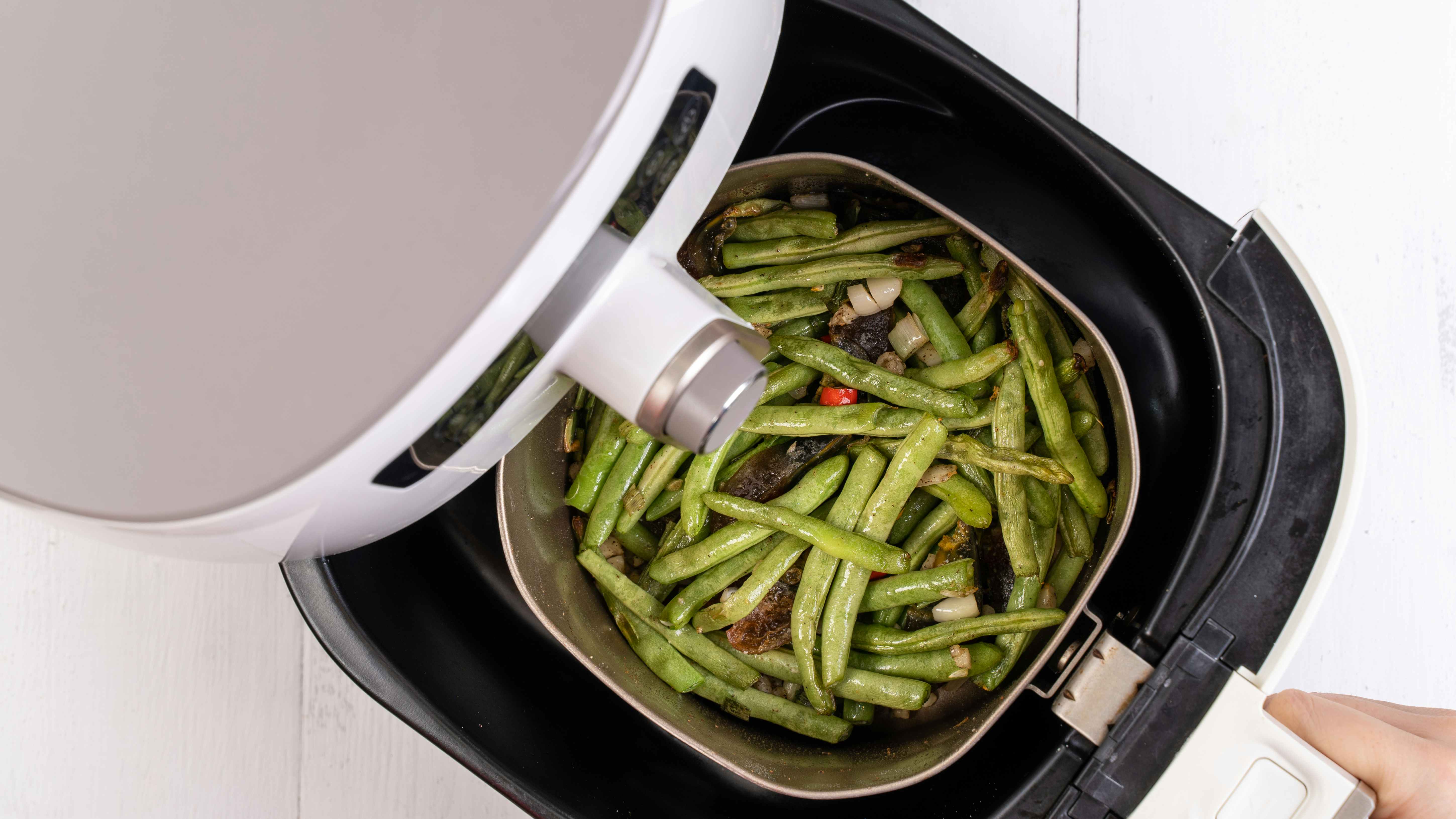 green beans cooking in an air fryer tray 