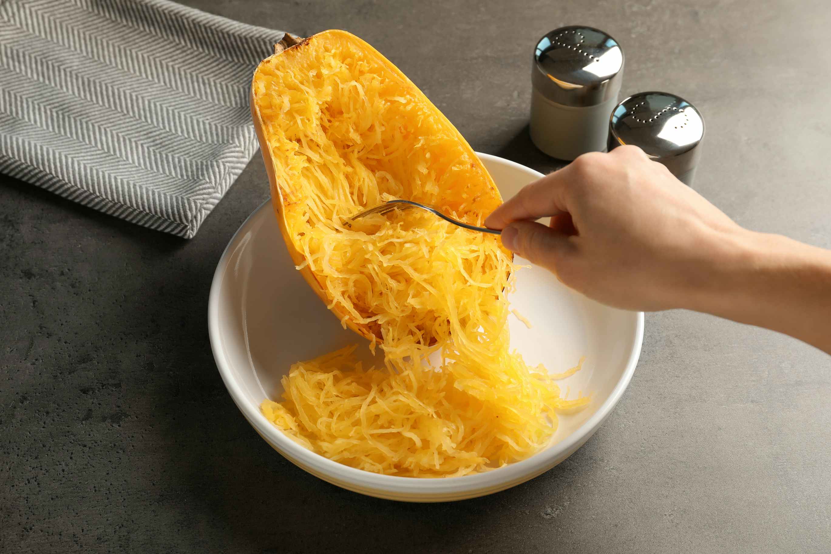 a person scooping spagetti squash into a bowl 