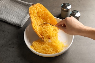a person scooping spagetti squash into a bowl