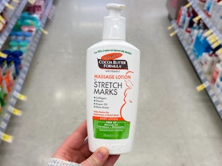a person holding palmers cocoa butter lotion in a store