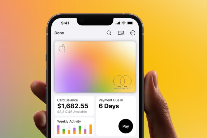 Hand holding an iPhone with the Apple Card interface shown.