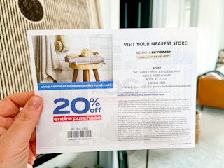 a person holding a bed bath and beyond coupon