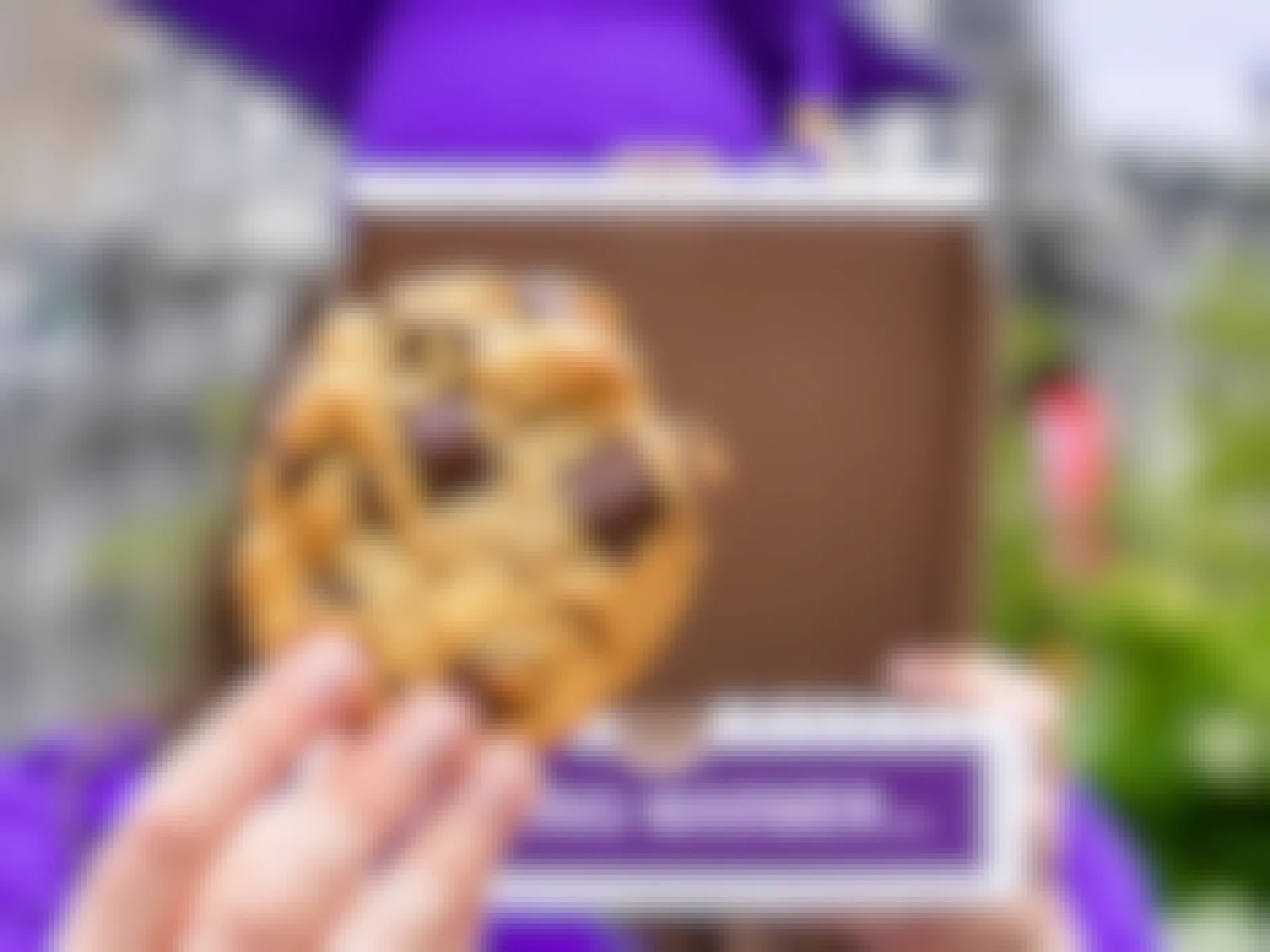 graduate holding a chocolate chunk insomnia cookie and box