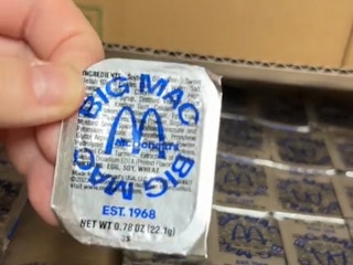 a person holding a big mac sauce cup