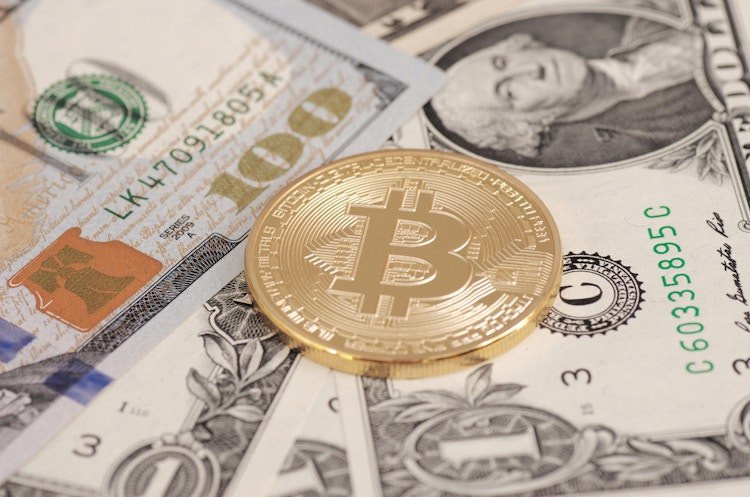 A coin representing Bitcoin on top of some cash