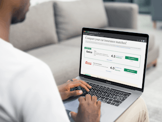 Someone sitting on a couch using a laptop to compare auto insurance policies