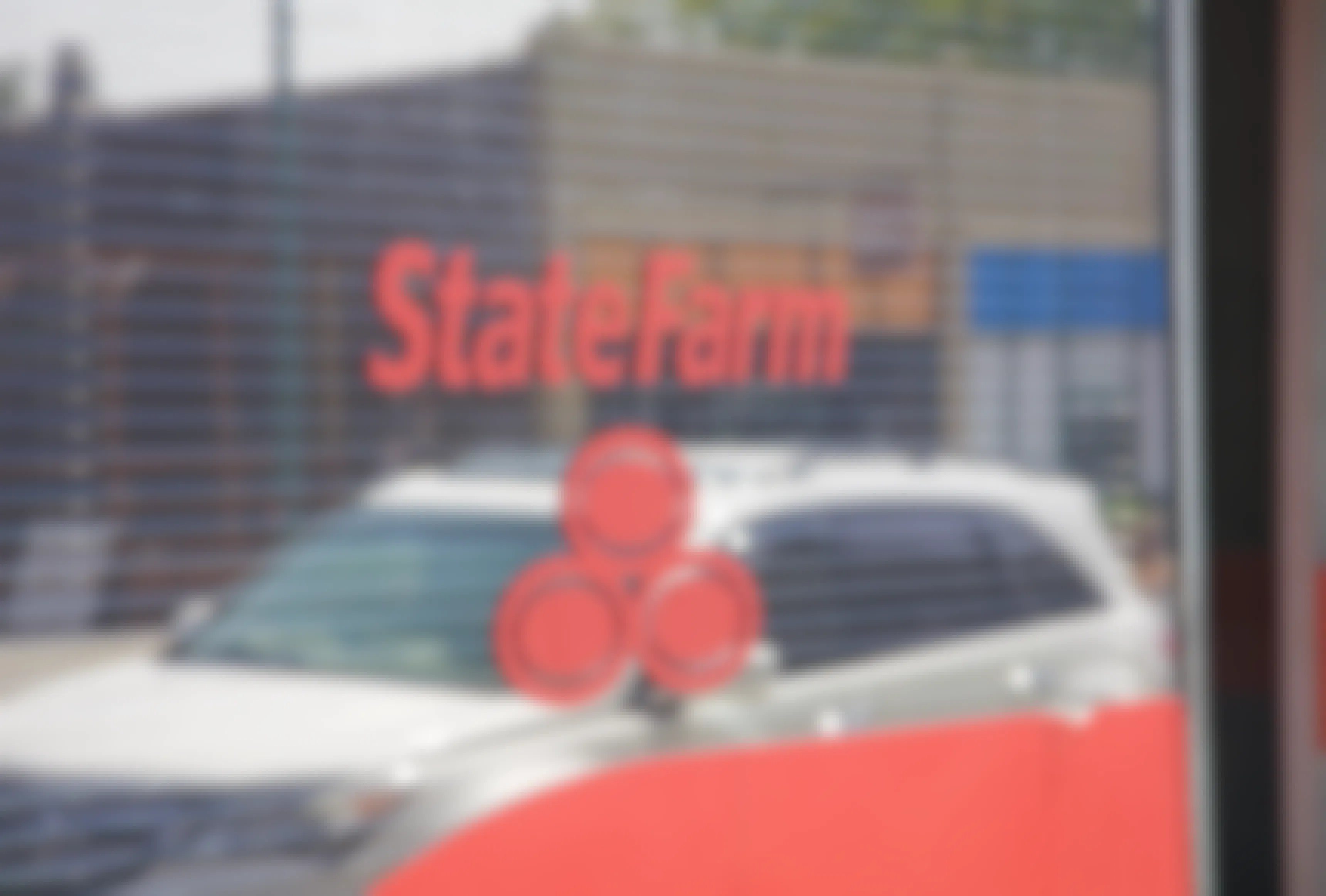 A car reflected in the window of a State Farm building