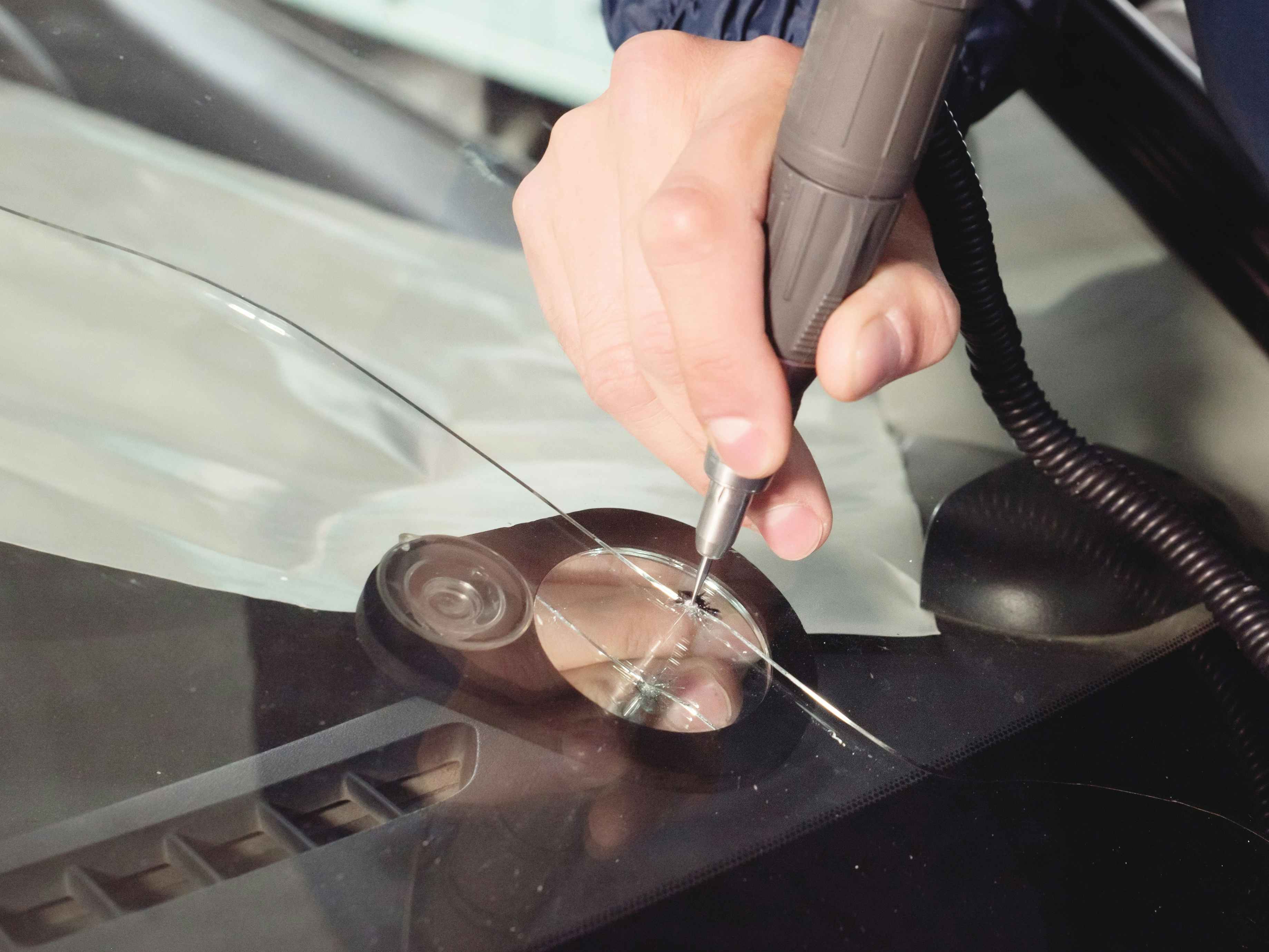 a person fixing a crack in a windshield 