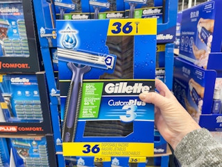 a person holding up a pack of razors in store