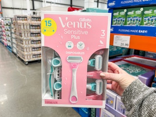 a person holding up a pack of razors in store