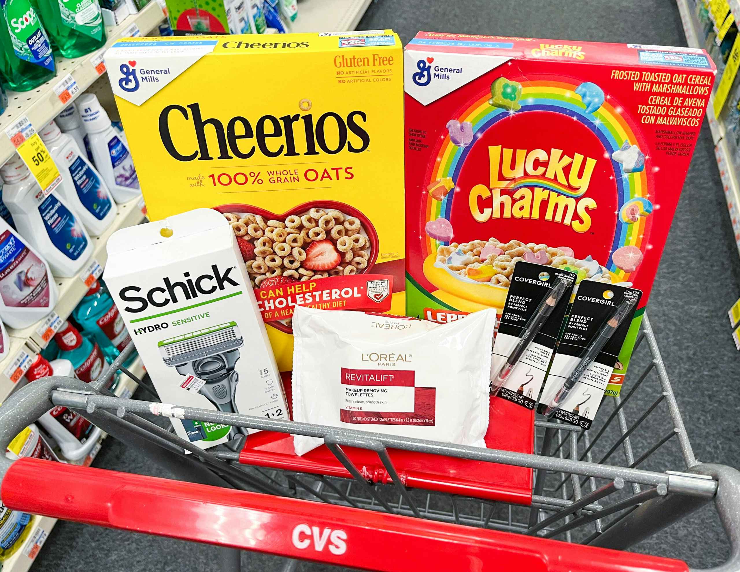 shopping cart with Cheerios cereal, Lucky Charms cereal, Schick razor, L'Oreal Paris Revitalift makeup remover wipes, and two Covergirl eyeliners inside