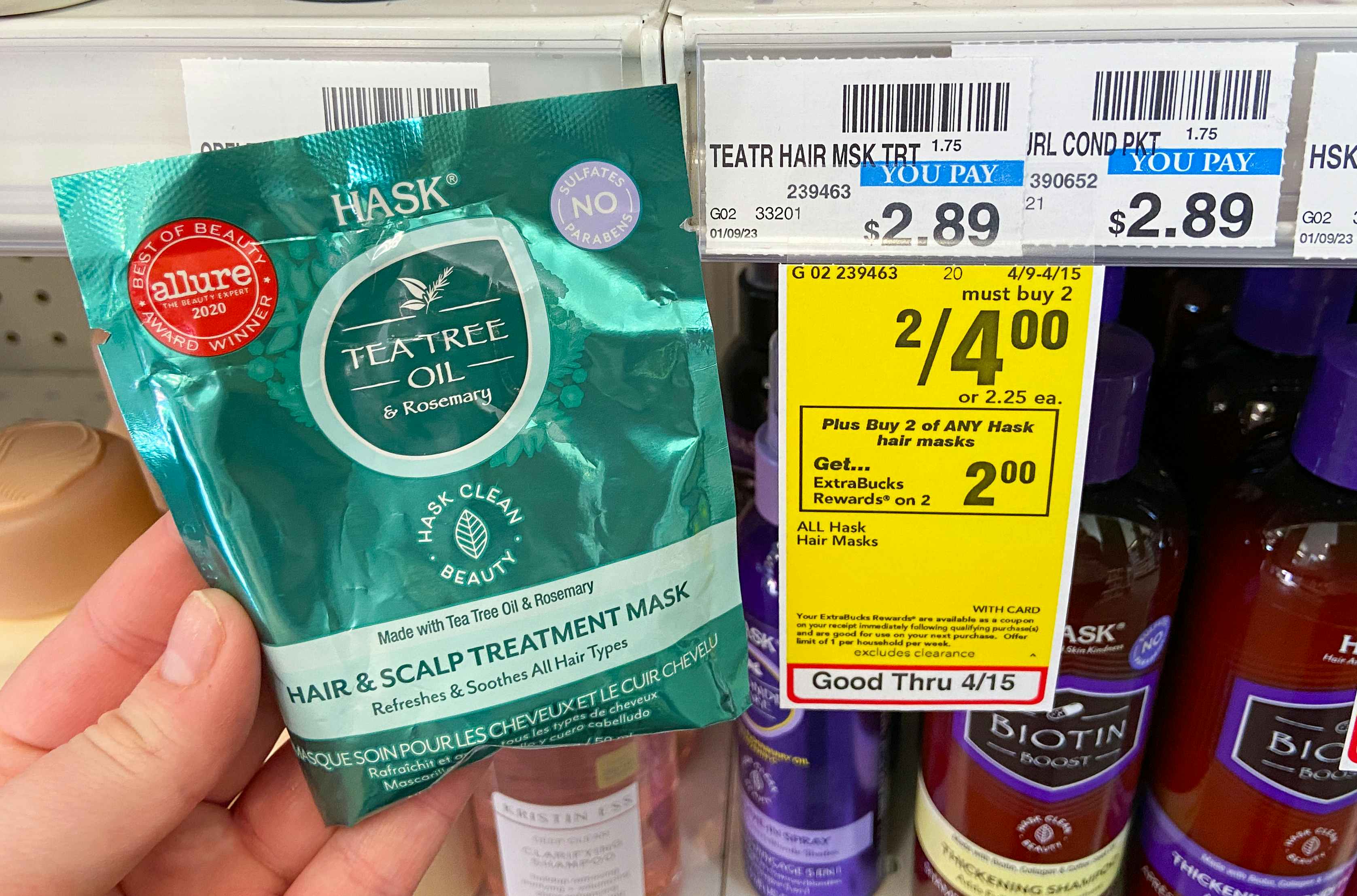 hand holding hask hair mask sachet next to a cvs sale tag