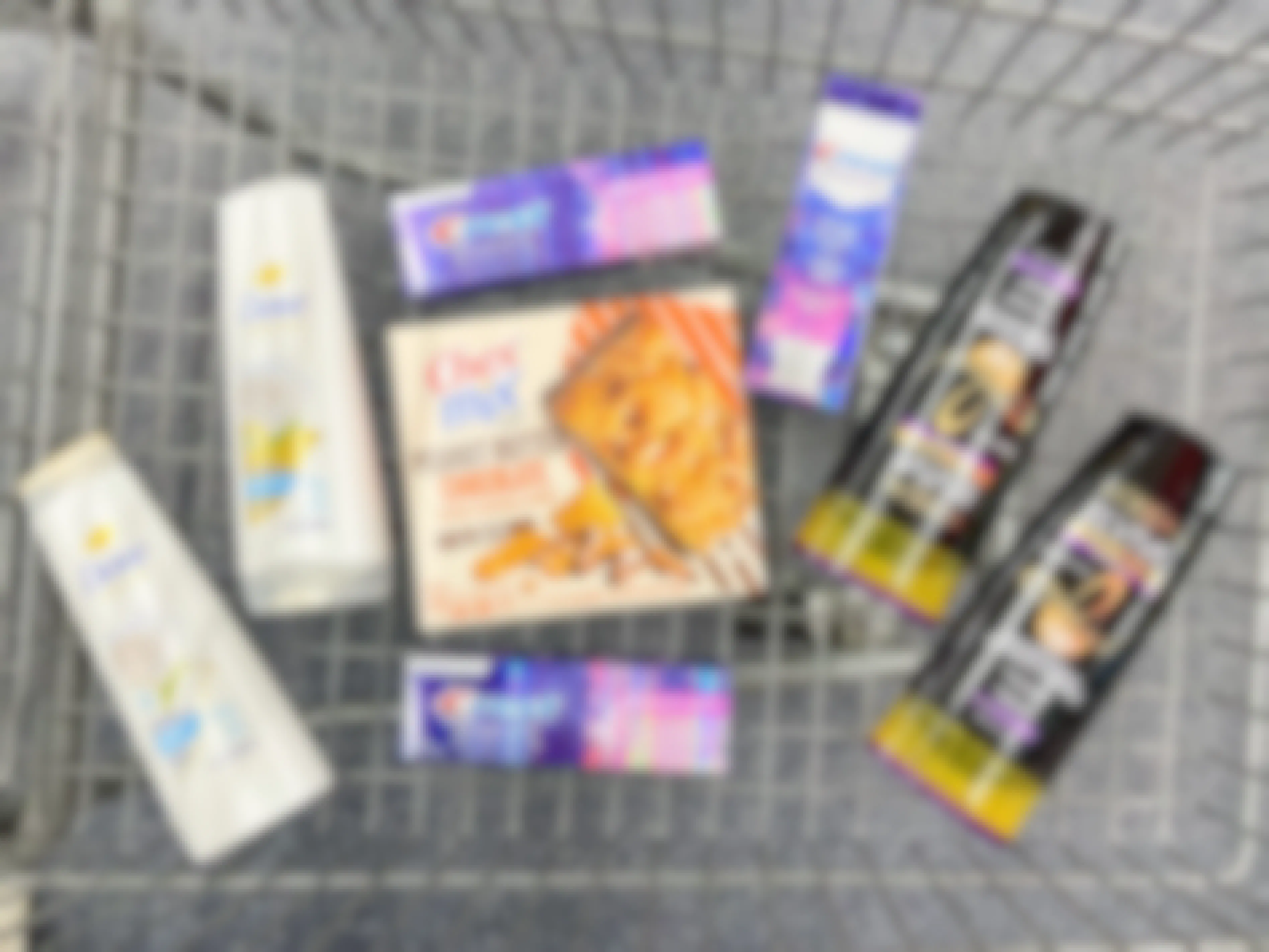 a cvs shopping cart filled with grocery items, l'oreal and dove shampoo and conditioner, chex mix cereal bars, crest toothpaste