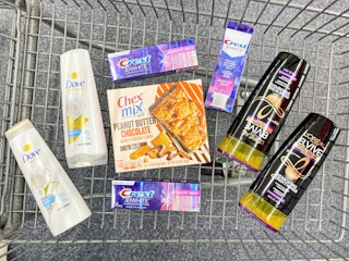 a cvs shopping cart filled with grocery items, l'oreal and dove shampoo and conditioner, chex mix cereal bars, crest toothpaste