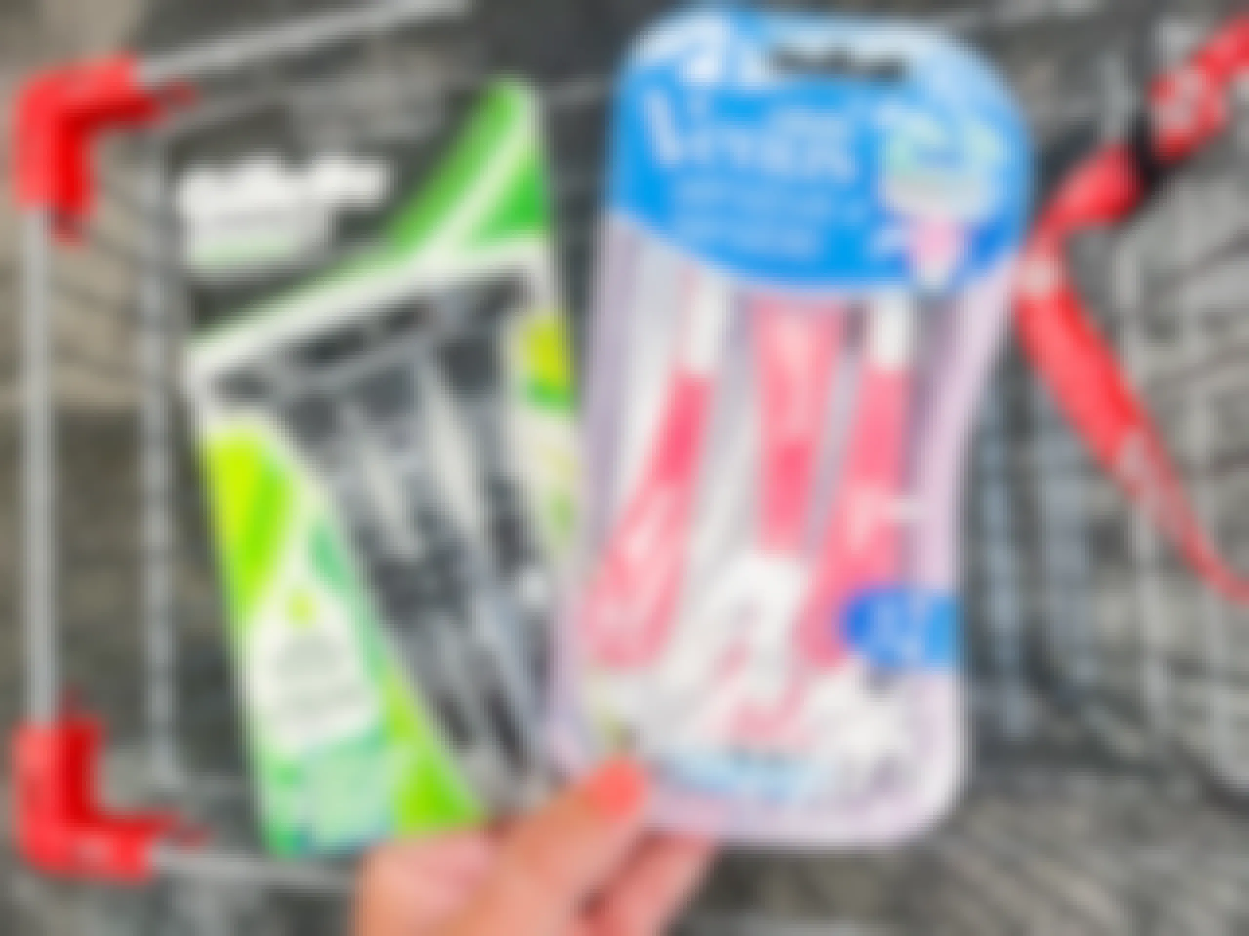 hand holding pack of Gillette Mach3 razors and Gillette Venus Sensitive razors in front of shopping cart